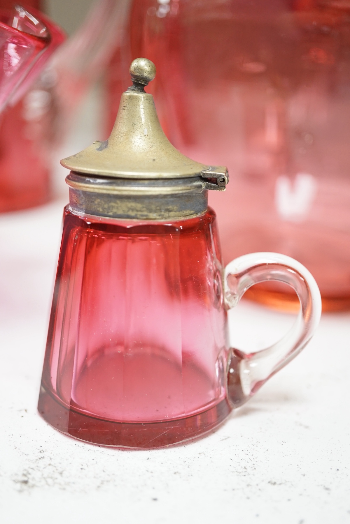 A quantity of cranberry glassware to include pair of vases with trailed decoration, jugs and an oil lamp, largest 38cm high. Condition - fair, some chipping